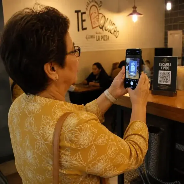Mujer mayor escaneando un código QR para pedir en un restorán